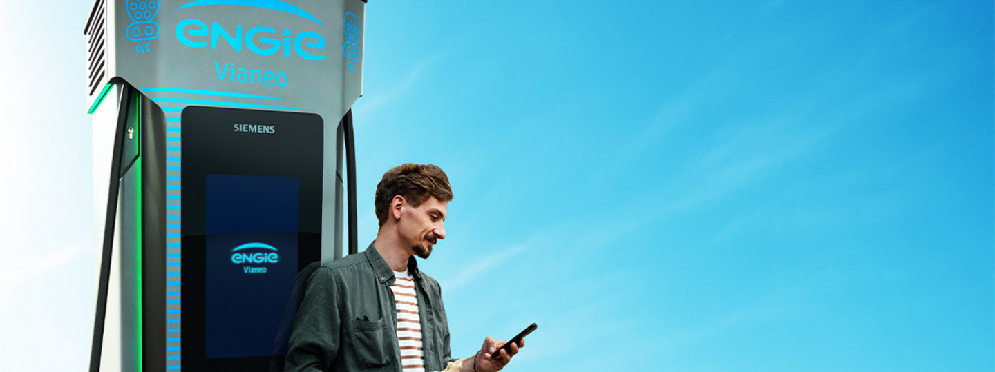 Mann mit Handy an E-Ladesäule, E-Mobilität