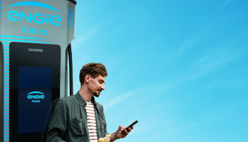 Mann mit Handy an E-Ladesäule, E-Mobilität